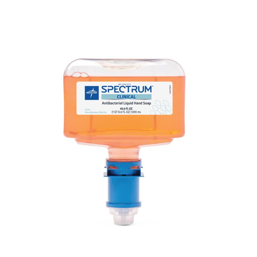 A clear plastic dispenser holds orange Medline Spectrum Antibacterial Liquid Hand Soap, labeled Spectrum Clinical, with a blue mounting cap and nozzle, designed for use in commercial soap dispensers.